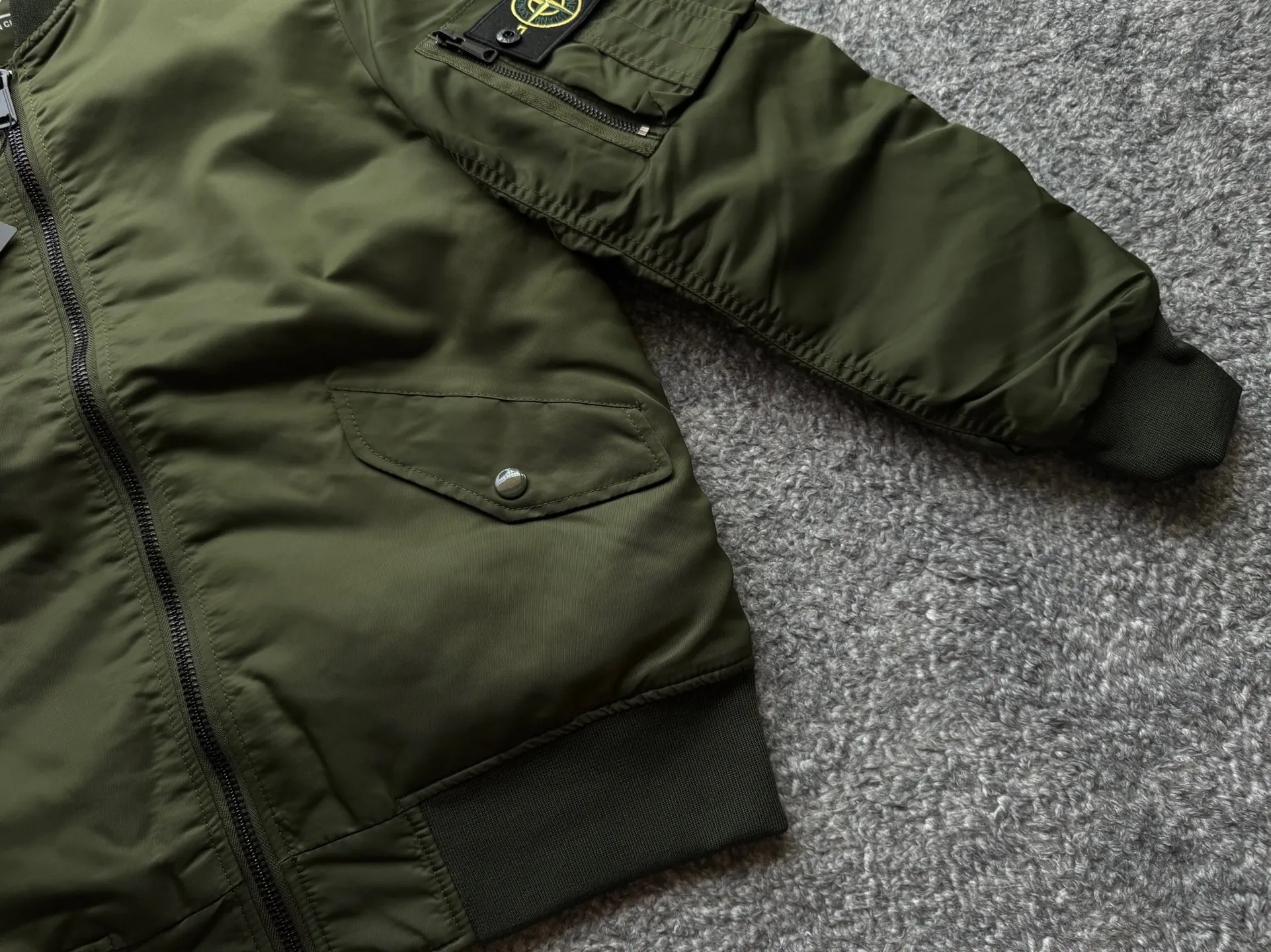 P360 Stone lsland Stone Island Medal Aviator Cotton Jacket The outer fabric is made of MA-1 flight nylon, which is a material specially used in flight and aviation. Flying nylon is a fabric specially used in flight and aviation. It is rarely used in ordinary clothing. The density of flying nylon is very high, so it is windproof and waterproof. When rain falls on the surface of the clothes, it will not penetrate immediately, but will form a small water droplet and slide off. This performance is a requirement for the development of modern jet technology. Because it is assumed that the pilot got caught in the rain before getting on the plane, he entered the cabin covered in rainwater. When flying at high altitude and at high speed, in a cabin without an environmental control system, water droplets will freeze on the pilot's body 2. Knitted baseball collar MA-1 uses a knitted collar. The collar is made of wool and can be snug around the neck and very warm. 3. Metal zippers We have very strict requirements on zippers, including smoothness and size. There was no zipper on the market that met the requirements, so we asked a zipper factory to customize a strong and durable metal zipper.  4. Double-threaded knitted cuffs The cuffs are made of double-threaded knitted fabric, narrow at the front and wide at the back. The narrow part can be tightened around the wrist to prevent wind from entering. The wide part has enough space when wearing multiple pieces under winter Color: Black Dark Army Green Size: M L.